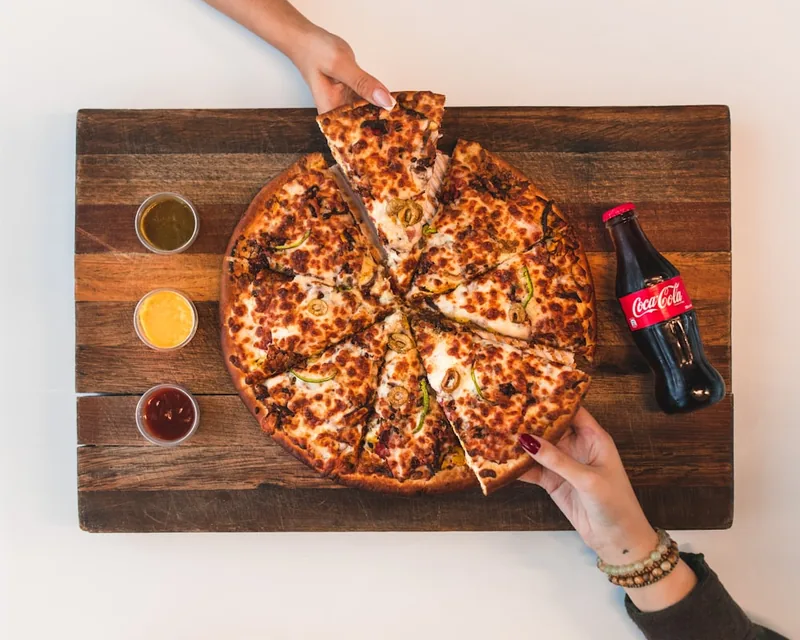 Hands reaching for slices of a fresh pizza