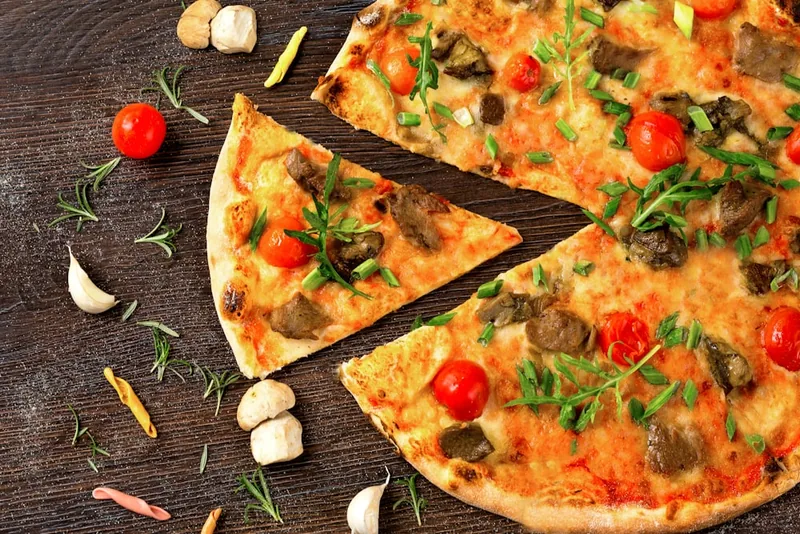 A slice of pizza topped with rocket and cherry tomatoes