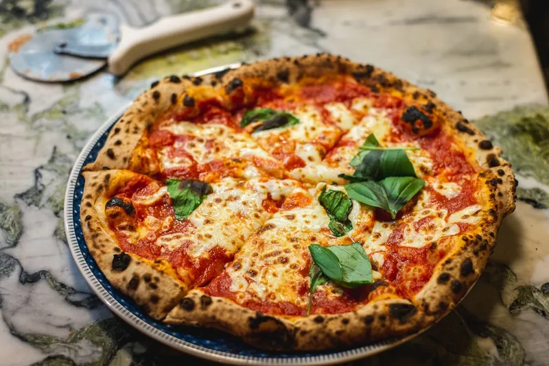 A coal-fired pizza with blistered crust and bubbling mozzarella fresh from the oven